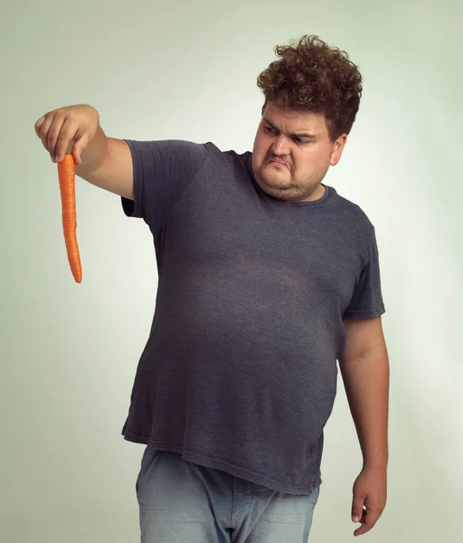 このオレンジの棒は何ですか ニンジンを持った太りすぎの男が — ストック写真