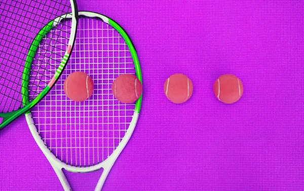 非常に多くの異なる色 スタジオ内の紫色の背景の上に配置されたテニス必需品の高角度ショット — ストック写真