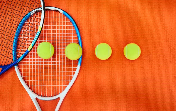 誰が先に行くでしょう スタジオ内のオレンジの背景の上に配置されたテニス必需品の高角度ショット — ストック写真