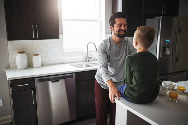 Hell always make time for his son. High angle shot of a handsome young man talking to his son while standing in the kitchen