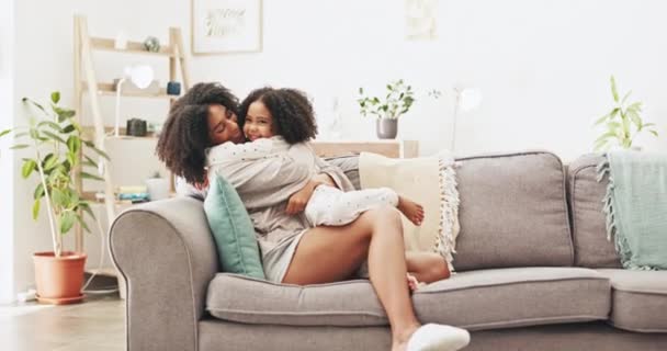 母亲抱着她的孩子 在客厅的沙发上放松 亲密和年轻的妈妈在家里悉心拥抱和亲吻她的女儿 — 图库视频影像