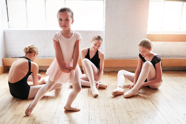 Dreams come true when you have courage to pursue them. an adorable little girl learning ballet with a group of older girls in a dance studio