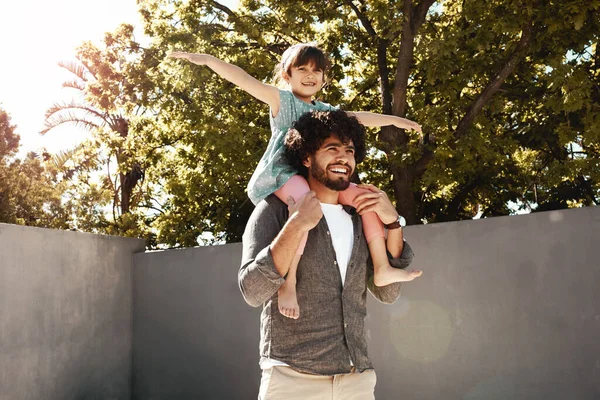 Stock image Dad makes every day so exciting. a father giving his little daughter a piggyback ride outdoors