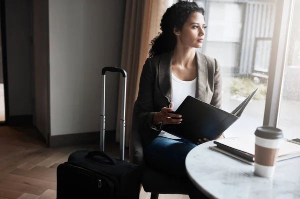 Stock image Let your ambitions take flight. a young businesswoman reading through a business folder while waiting for her flight in an airport lounge