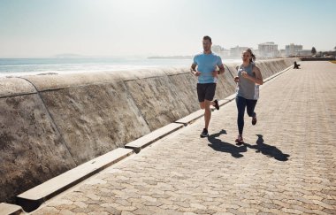 Theres no shortcut to fitness. Full length shot of a young couple out for a run on the promenade clipart