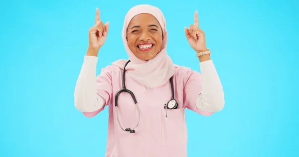 イスラム教徒の看護師 幸せな女性と健康 宗教や幸福のためのスペースと指の肖像画を指す 青色の背景に発表のための手 笑顔とヒジャーブとイスラム女性医療従事者 — ストック写真