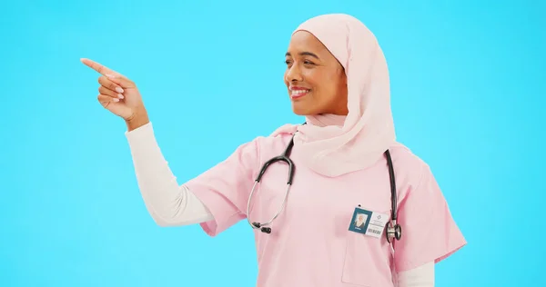 青色の背景に隔離されたスタジオでモックアップを指す顔 看護師 イスラム教徒の女性 肖像画 医療専門家とマーケティング 広告や製品の配置と幸せなイスラム教の人 — ストック写真