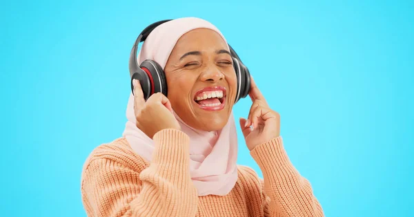 幸せな女性 ヘッドフォンやダンスの青の背景のお祝いや歌のための音楽を聞いて孤立した スタジオでストリーミング技術を持つ面白い ダンスやイスラム教徒 ジェンZやヒジャーブ人 — ストック写真