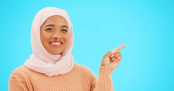 穆斯林妇女 快乐而形象地将手指指向空间进行模仿 做广告或促销 带着手 笑和头巾的伊斯兰女性 用于发布或销售蓝色背景的产品 — 图库照片