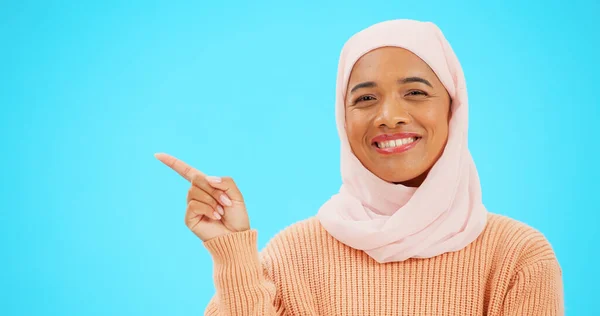 モックアップのための手で幸せなイスラム教徒の発表のための指とスペースを指して スタジオブルーの背景に販売 プロモーションや製品の配置のための笑顔でヒジャーブと顔を持つイスラム女性 — ストック写真