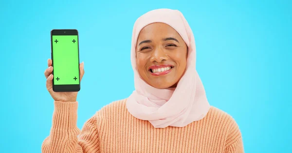 イスラム教徒 携帯電話や緑の画面とスタジオでのトラッキングマーカーとディスプレイを保持する青色の背景の女性 イスラム教 モバイル接触とマーケティングのための画面を示す魅力的な若い女性 — ストック写真