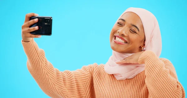 ソーシャルメディアのキス 笑顔と絵文字ポストオンラインのための青の背景に隔離されたイスラム教徒の女性のセルフィー スタジオでのプロフィール写真や影響力のあるライフスタイルの幸せなイスラムのゲンZやヒジャーブ人の顔 — ストック写真