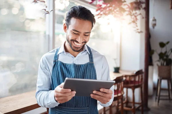 Restaurant, tablet and happy man or small business owner, e commerce and online cafe or coffee shop management. Waiter or asian person reading sales on digital technology or internet for his startup.