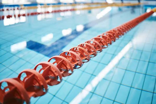 Water, empty swimming pool and lanes for competition, exercise and workout. Sports, swim and fitness with lane ropes or divider in liquid for aquatic training, exercising or underwater practice