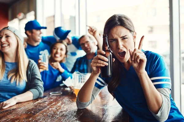 Guess who took home the trophy. Portrait of a woman holding up one finger while watching a sports game with friends at a bar