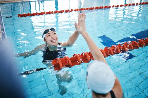 Swimming pool, sports and women high five in water for teamwork, collaboration or solidarity. Swimmer, happiness and friends or girls with hand gesture for support, success and celebration at workout.