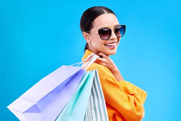 Shopping bags, studio and woman portrait with deal and happiness from boutique sale. Happy, customer and wealthy female model with store bag and sales choice in isolated blue background with person.