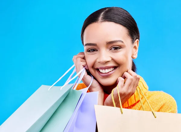 Shopping bags, studio and woman portrait with a smile and happiness from boutique sale. Happy, customer and female model with store bag and sales choice in isolated blue background with young person.