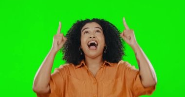 Stüdyoda ürün modellemesini desteklemek için yeşil ekran arka planda bir kadını işaret eden eller. El hareketi, mutlu ve kafasının üstünde boş kromakey alanı gösteren genç bir kadınla gülümsemek..
