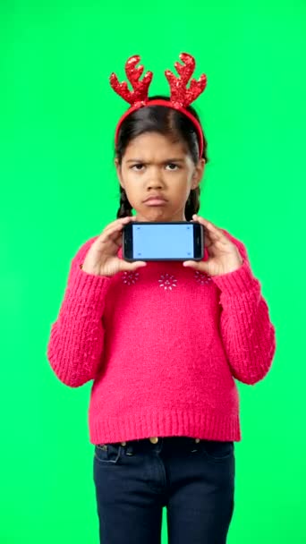 圣诞节的脸 绿色的屏幕和孩子与手机在工作室隔离的背景跟踪标记 因不想要的礼物而带着智能手机的调皮捣蛋 圣诞节和悲伤或不快乐的女孩 — 图库视频影像