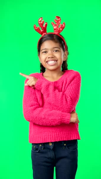 圣诞节 用手指或手指着绿色屏幕上的空间 带鹿角头带的兴奋女孩垂直工作室背景的微笑肖像 用于手工模拟节日庆祝 — 图库视频影像