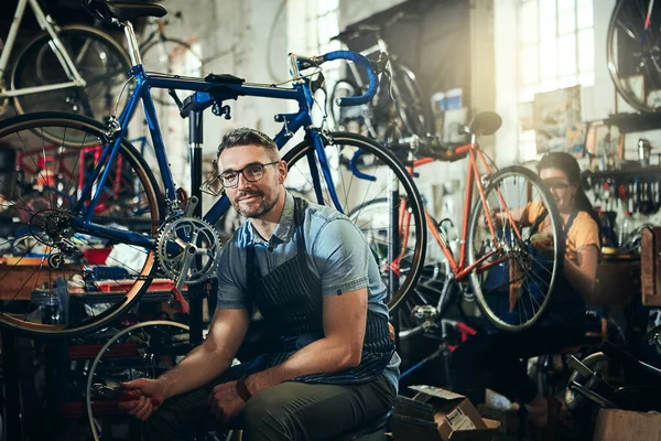 有自行车方面的经验 一个成熟男人和他的同事在自行车修理店工作的肖像 — 图库照片