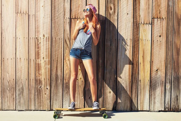 滑冰绝对应该在你的桶名单上 一个年轻女子和她的滑板一起在木板路上玩 — 图库照片