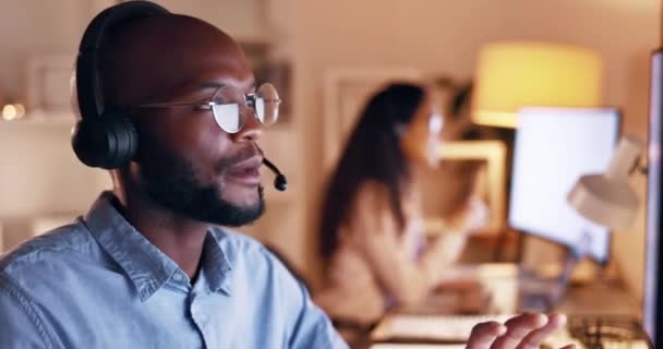 カスタマーサポートの話を聞きながら 夜のCrmオフィスで黒人男性 テレマーケティング コミュニケーション コールセンター 従業員の仕事と会話 技術支援についての相談 — ストック動画