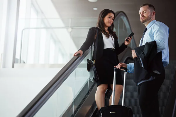 スマートビジネス旅行者はスマートテクノロジーを使用します 空港のエスカレーターを降りるビジネスマンやビジネスマンが — ストック写真