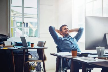 Üretken günler bu tatmin edici duyguyu uyandırır. Ofis masasında mola veren genç bir işadamı.