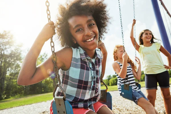 友達と新鮮な空気をお楽しみください 彼女の友人と公園でスイングで遊んでいる若い女の子の肖像画 — ストック写真