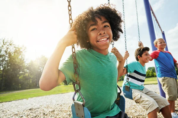 子供の健康的な発達には遊びが不可欠です 友達と公園でスイングで遊んでいる若い男の子の肖像画 — ストック写真