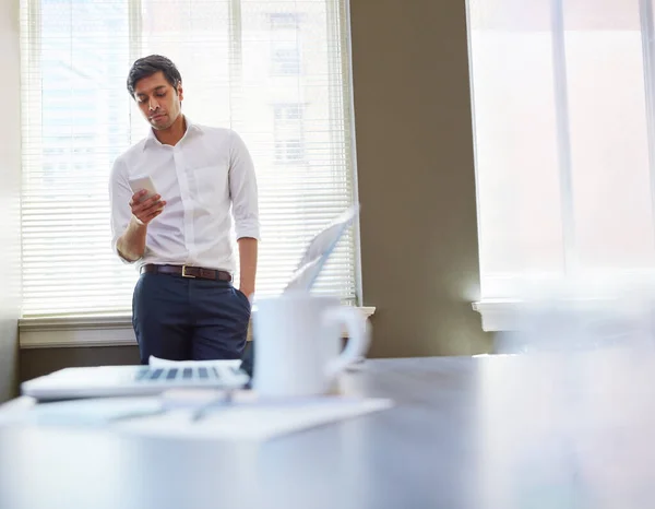 stock image Looks like my colleague is running late today. a businessman working on his smartphone in the office