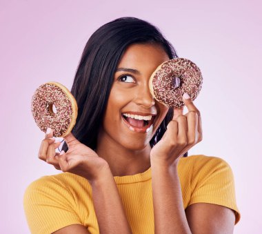 Donut, tatlı ve çikolatalı kadın diyet, aperatif ve mutluluk için stüdyoda. Şeker, yemek ve gülümseme, saklanan bir kadın ve pembe arka planda izole edilmiş beslenme, şakacı ve aşeren bir maket..