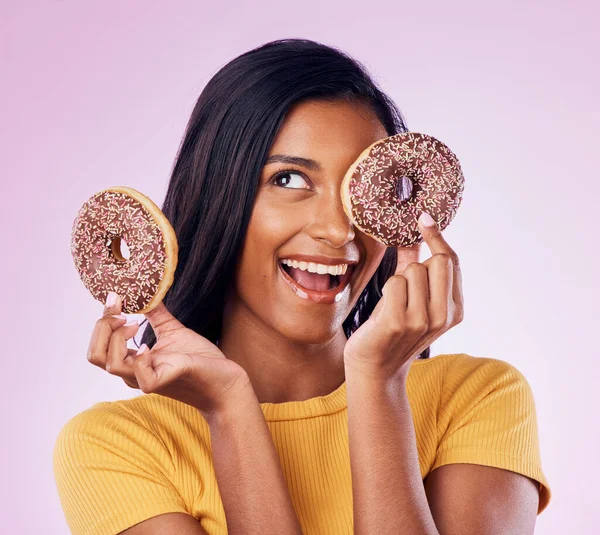 Donut, dessert and chocolate with woman in studio for diet, snack and happiness. Sugar, food and smile with female hiding and isolated on pink background for nutrition, playful and craving mockup.