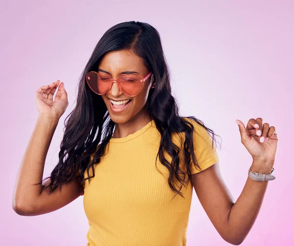Dancing, sunglasses and cool woman excited, happy and confident isolated in a pink studio background with joy. Singing, music and young genz female dance in celebration of a party energy with glasses.