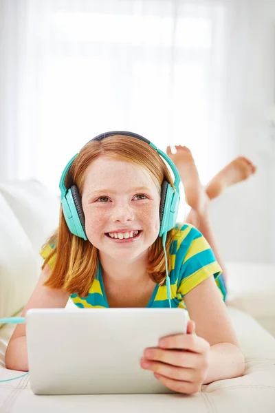 stock image Growing up in a connected world. a little girl using a digital tablet with headphones at home