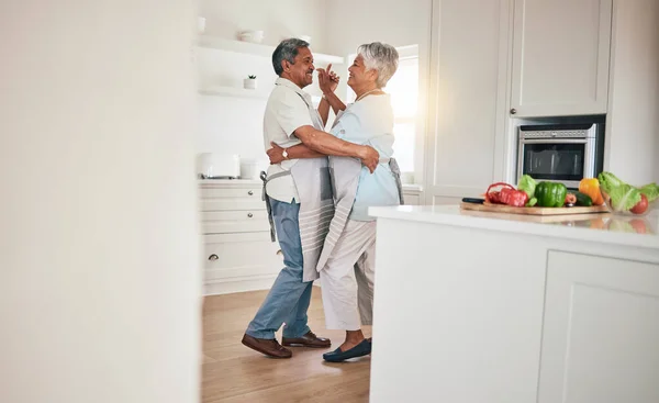 stock image Happy, cooking or elderly couple dance in the kitchen together and feeling love, excited and bonding in home. Care, happiness or romantic old people or lovers dancing and enjoying retirement in house.