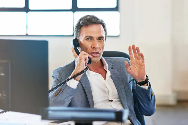 No excuses, just get it done. a mature businessman making a serious call on the phone at work