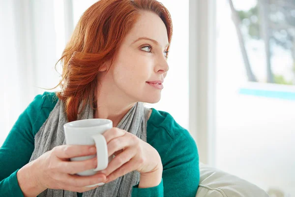 コーヒーと熟考 自宅のソファでリラックスしながら大人の女性がコーヒーを飲み — ストック写真