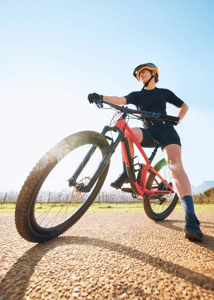 Bicycle break, ride and woman on a bike from below for sports race on a gravel road. Fitness, exercise and athlete doing sport training in nature or countryside for cardio rest and healthy workout.