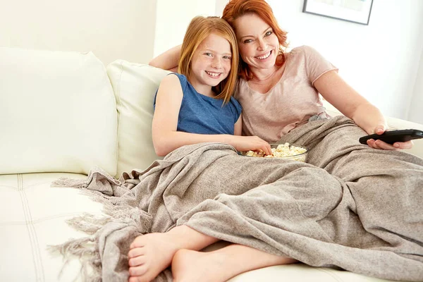 stock image Movie night. a mature woman and her young daughter watching a movie and eating popcorn on the sofa