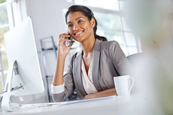 Shes rated highest for client satisfaction. a young businesswoman talking on the phone while sitting at her office desk