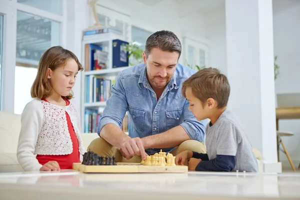 stock image Learning the game. a father playing a game of chess with his son and daughter at home