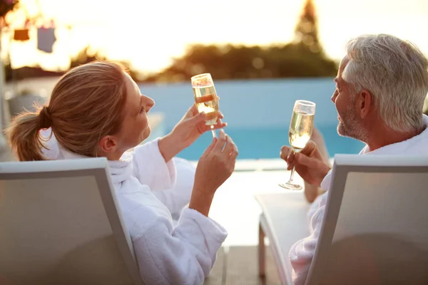 ロマンチックな休暇で 夕暮れ時にデッキチェアでリラックスしながら 成熟したカップルの飲酒シャンパンのレビューショット — ストック写真