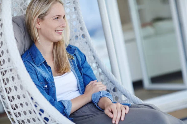 stock image Not a care in the world. an attractive young woman relaxing in a hanging basket chair on her patio