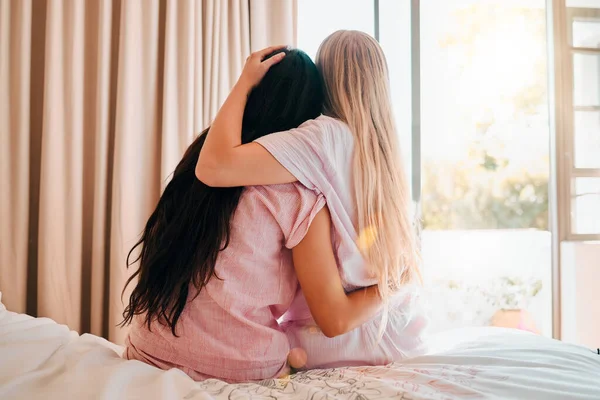 Love, bedroom and back of friends hugging for comfort, support or care while at a sleepover. Bond, romance and lesbian women couple embracing and spending quality time together in their apartment