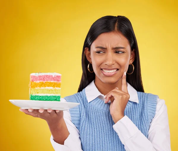 誕生日のお祝い 災害や間違いを考えながら 動揺の女性 虹のケーキやスタジオ 黄色の背景に色 悪臭や悪いアイデアを持つデザート食品とインドのGen Z女性の顔 — ストック写真