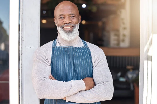 Black man, portrait smile and arms crossed in small business cafe or retail store by entrance door. Happy African American senior businessman standing in confidence at restaurant or coffee shop.