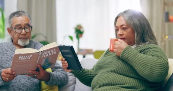 阅读和咖啡 老夫妇一起坐在沙发上看书在客厅里成熟的关系 退休和爱情 男人和女人在家里享受着饮酒 电子书和高质量的时光 — 图库视频影像